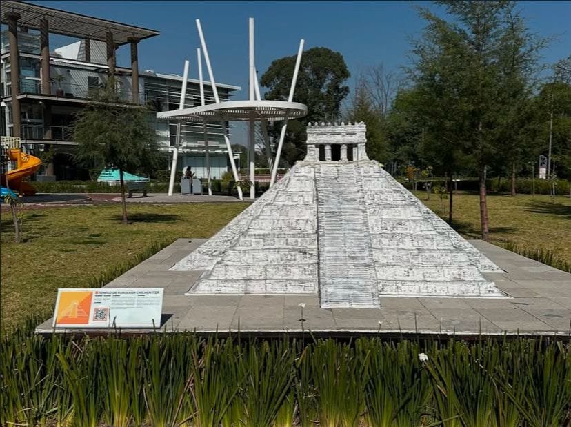Maqueta a escala del Templo Kukulkán de Chichén Itzá, México también conocido como El Castillo, exhibida en el Paseo de los Gigantes en Puebla, representando el patrimonio maya. Se observa césped y en el fondo se ven edificios.