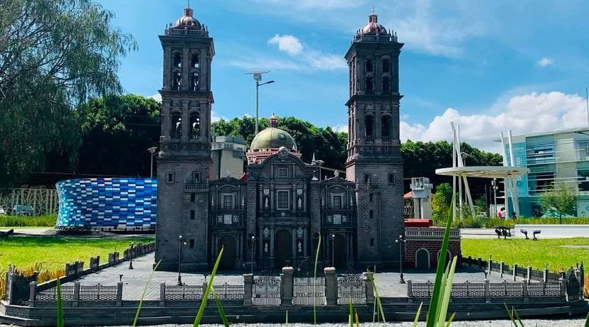 Maqueta a escala de la Catedral de Nuestra Señora de la Inmaculada Concepción Puebla, México, exhibida en el Paseo de los Gigantes en Puebla, al fondo se observa la maqueta a escala del estadio Cuauhtémoc de Puebla, además de edificios. Se observa a simple vista césped.