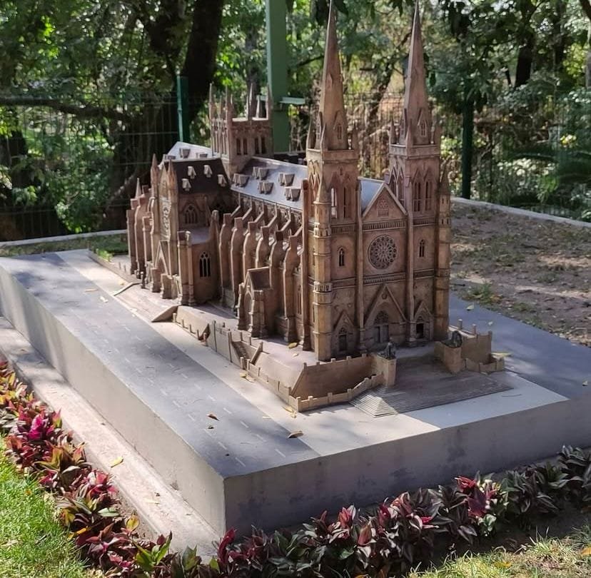 Maqueta a escala de la Catedral de Santa María de Sídney, Australia, exhibida en el Paseo de los Gigantes en Puebla. Al fondo hay vegetación verde. La estructura de la maqueta esta rodeada de plantas