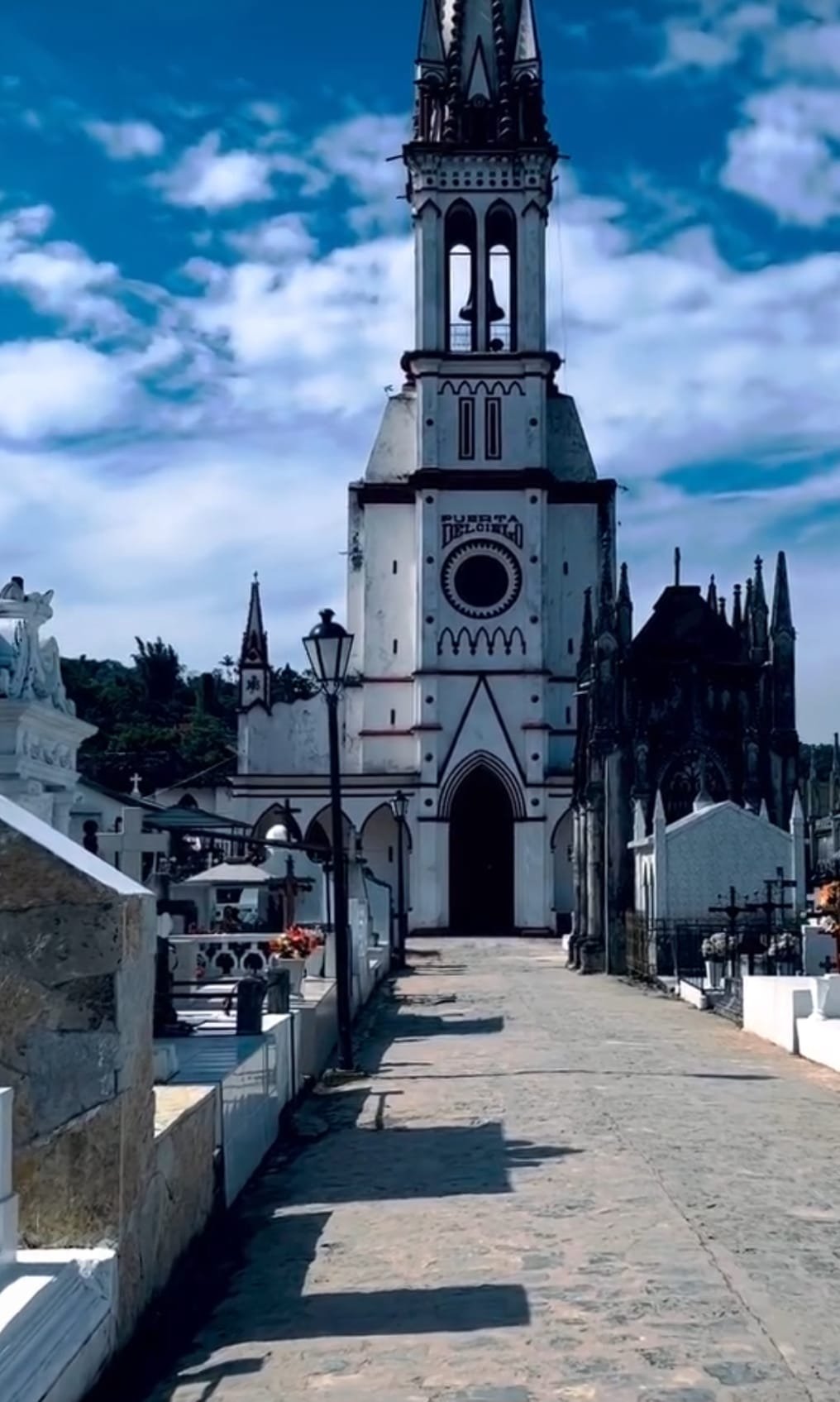 Se observan algunas lápidas en ambos lados adelante de la Iglesia de los Jarritos, que predomina su gran altura y su color blanco con detalles rojos.
