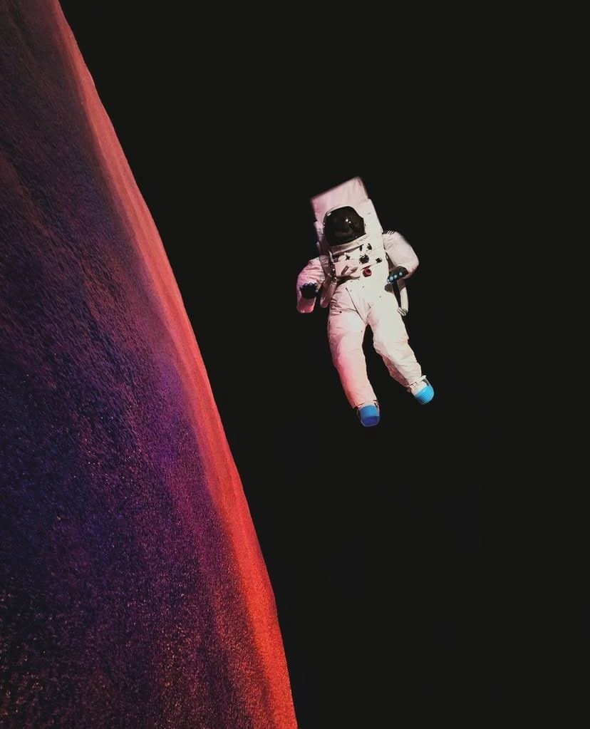 Obra exhibida en el Planetario de Puebla, en donde hay un astronauta flotando en el espacio cerca de la superficie de un planeta, con un fondo oscuro y un borde planetario iluminado en tonos naranjas.